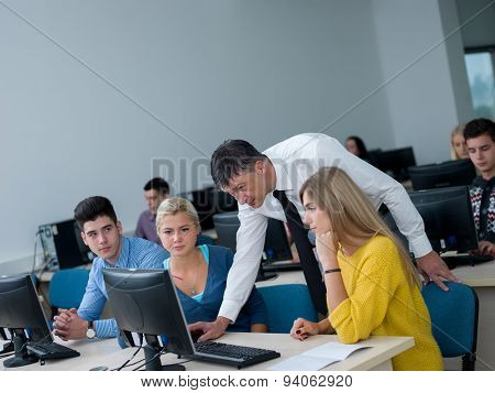 group of students with teacher in computer lab classrom learrning lessons,  get help and support