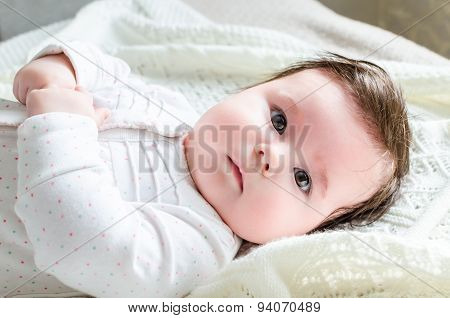 Cute Newborn Baby Girl In Romper Suit Lying On Woolen Blanket