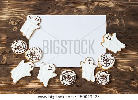 Funny delicious ginger homemade biscuits for Halloween on the dark wooden table with sheet of papper as a space for text. horizontal view from above. Halloween cookies