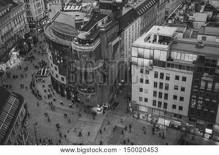 VIENNA AUSTRIA - FEBRUARY 9 2016: Crowd of people at the Stephansplatz. Aerial night view of famous landmark with many shops restaurants bars and modern buildings. Black and white