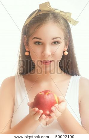 Young beautiful woman in a white T-shirt with a bow on her hair holding a peach in her hands. White background