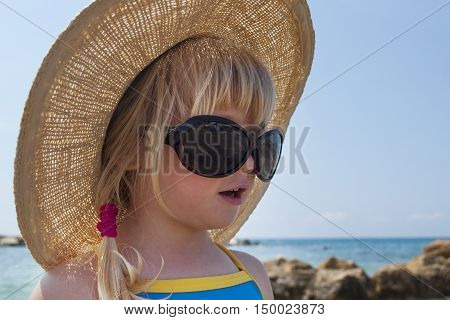 Toddler girl looks in Audrey Hepburn - style glasses on holiday