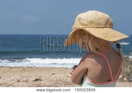 Adorable thinkful little girl at white beach during summer vacation