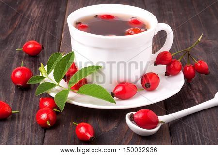 cup with rose hip tea on a dark wooden background.