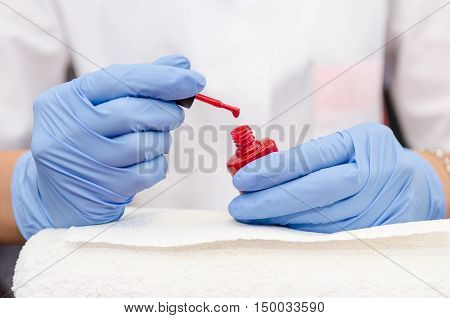 Female Hand With Gloves Opens A Bottle Of Red Lacquer