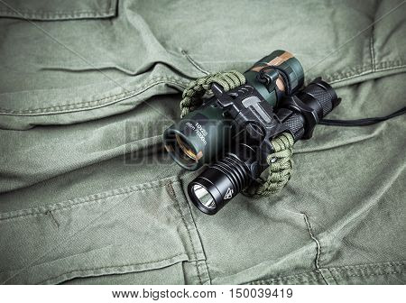 Military paracord bracelet, tactical torch and spy-glass on army-green fabric