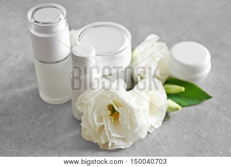 Cosmetic bottles and eustoma flowers on light wooden background
