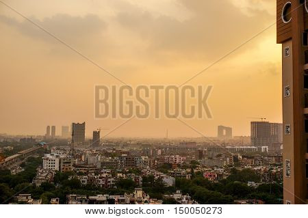 Evening falling over the buildings of Noida during the golden hour. The monsoon clouds mix with the dust over the still under construction buildings