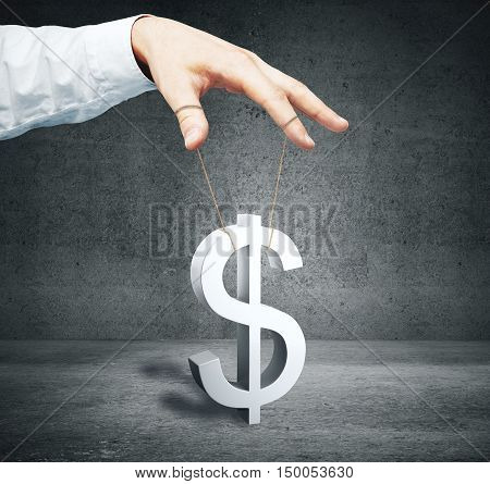 Male hand controlling dollar sign as puppet on concrete background. Price manipulation concept