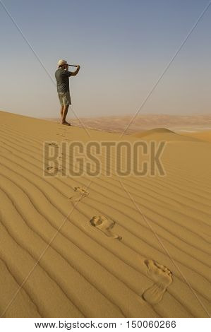 Man looking through spyglass in a desert