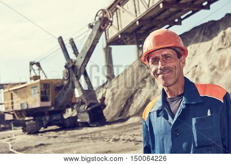 worker in front of heavy excavator loading gravel into train