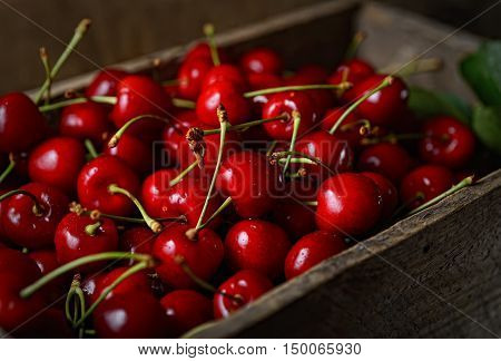 juicy red cherries in a wooden box on a dark background