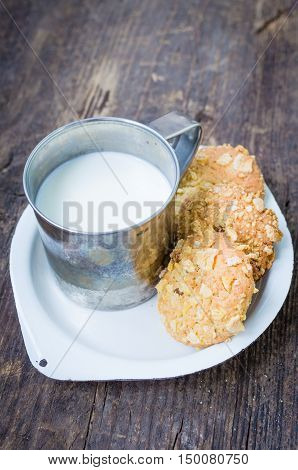 Homemade cornflakes and raisins cookies with cup of milk on old wooden table. Freshly baked corn flake cereal cookies on rustic background. Selective Focus.