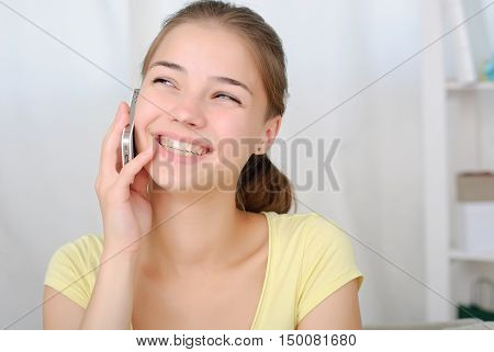 portrait of beautiful girl talking by phone in living room