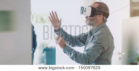 Mature business man wearing virtual reality googles / VR Glasses to work with in modern office