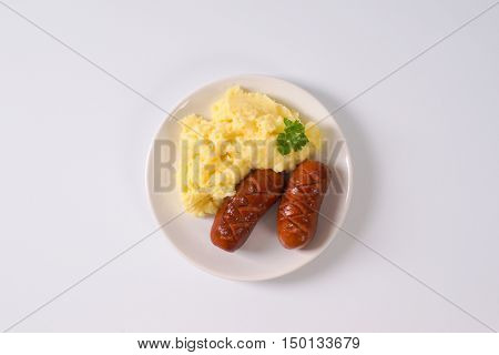 roasted short thick sausages with mashed potato puree on white plate