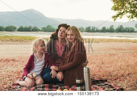 Caucasian mother and her two daughter together have a picnik in the park
