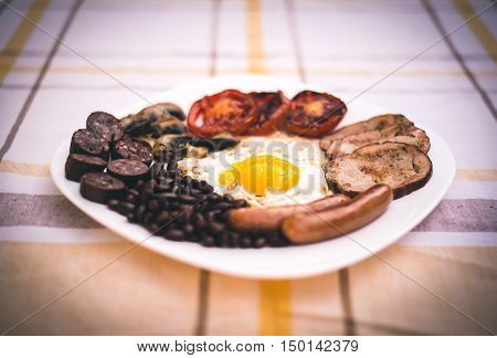 Full English fried breakfast with bacon, egg, sausages, black pudding, mushrooms. Grilled tomatoes and baked beans.