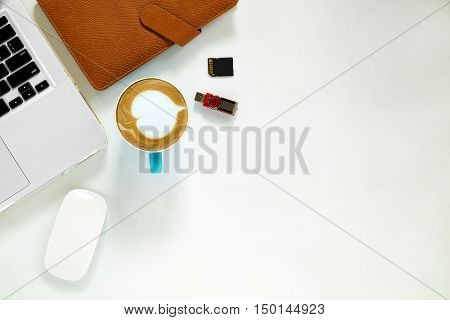 White office desk table with laptop computer mouse storage card cup of coffee and leather notebook. Top view with copy space.Office desk table concept.