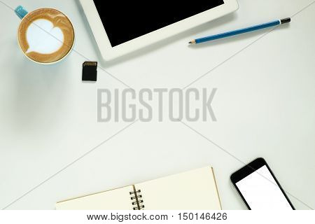 White office desk table with blank screen tablet smartphone pencil leather notebook sd card and cup of coffee. Top view with copy space.Office desk table concept.