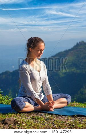 Sporty fit woman practices yoga asana Baddha Konasana - bound angle pose outdoors in HImalayas mountains in the morning with sky. Himachal Pradesh, India