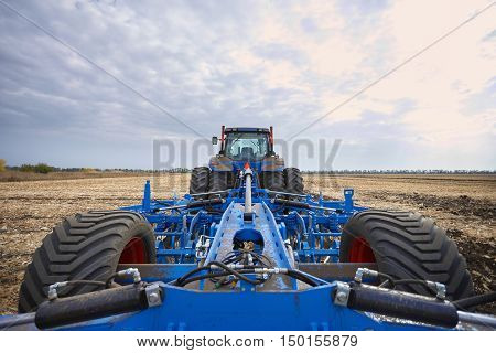Farmer riding a tractor, a tractor working in a field, agricultural machinery in the work, tractor in the background cloudy sky