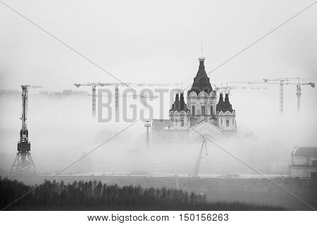 Cathedral of St. Alexander Nevskiy in Nizhny Novgorod Russia covered with fog. Numerous construction cranes. Black and white
