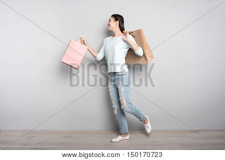 Happy after shopping. Positive delighted woman holding packages and going resting after visiting shops while expressing positivity