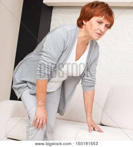 Adult woman has pain in the knee. Mature female at home
