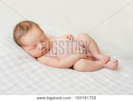 lovely newborn girl sleeping on pink blanket with bare feet