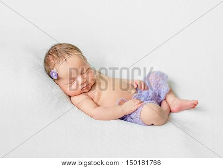 lovely sleeping newborn girl with hands under head in violet knitted panties