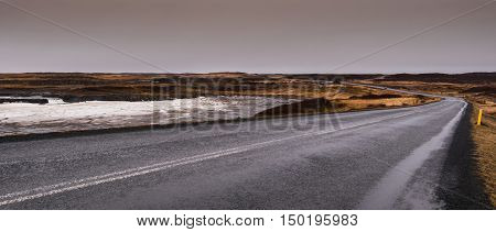 Highway countryside straight road with with icy frozen lake on the side at Snæfellsnes Peninsula in Iceland