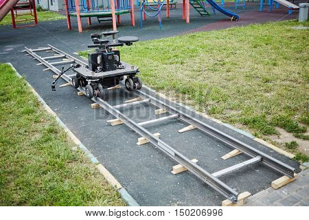 Cameraman dolly stands on rails mounted at children playground.