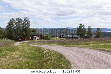 HARJEDALEN, SWEDEN ON JULY 07. View over buildings, gravel road and the landscape on July 07, 2016 in Harjedalen, Sweden. Summer and farmland. Editorial use.
