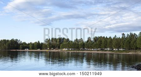 MEDELPAD, SWEDEN ON JULY 09. View of a campsite, car, campers and caravan on July 09, 2016 by Holmsjon, Sweden. Sunny summer day. Pine forest and a lake. Editorial use.