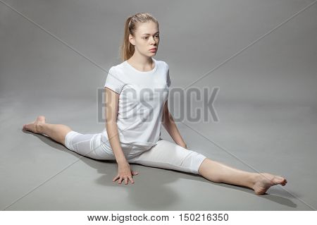 Young Beautiful Woman Makes Exercises On Gray Background