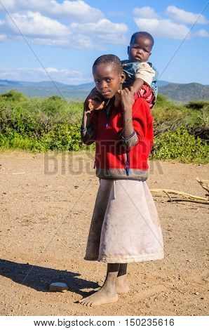 LAKE EYASI, TANZANIA - MAY 29, 2015: Older brother carrying the younger one in a Datoga Tribe at Lake Eyasi Tanzania