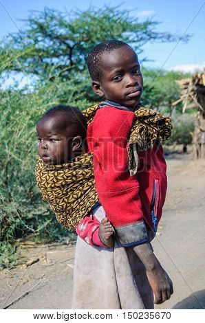LAKE EYASI, TANZANIA - MAY 29, 2015: Older brother carrying the younger one in a Datoga Tribe at Lake Eyasi Tanzania