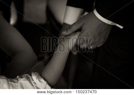An adult's hand holding a child's hand. Could be a father, might be a son.