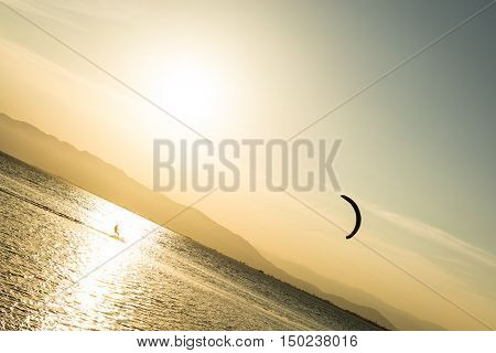 Kitesurfing in the bay at sunset, triyng to hold the kite