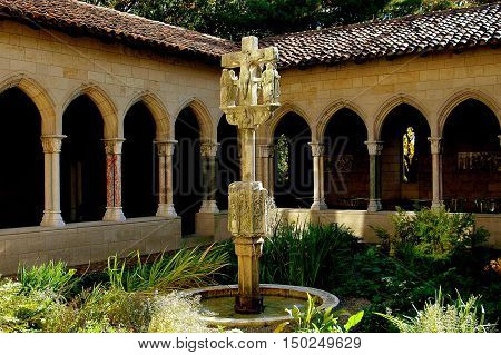 New York City - November 3, 2005: 16th century Calvaire with fountain stands at the center of the Trie Cloister medieval garden at the Cloisters Museum of Medieval Art