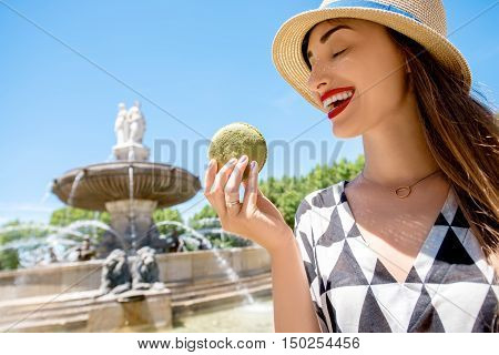 Young female tourist with macaron cookie near the famous fontain de la Rotonde in Aix-en-Provence in France