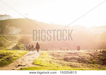 People walking through a park facing the sun