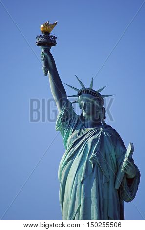 Upper half of the Statue of liberty taken against a clear blue sky.