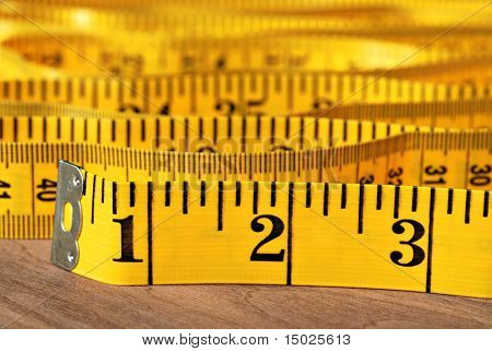 Mètre ruban lumineux jaune sur bois.  Macro avec dof extrêmement faible.