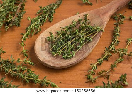 Fresh Thyme into a spoon over a wooden table