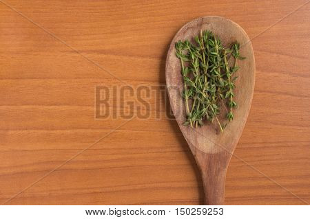 Fresh Thyme into a spoon over a wooden table