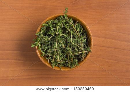 Fresh Thyme into a bowl over a wooden table