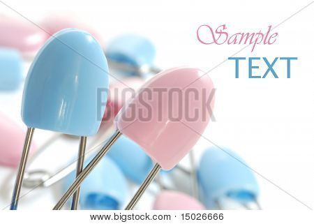 Blue and pink diaper pins on white background with copy space.  Macro with extremely shallow dof.
