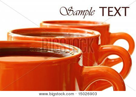 Rækken af lyse orange krus fyldt med kaffe eller te på hvid baggrund med kopi rum.  Makro med